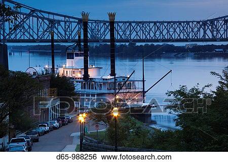 Stock Photograph - USA, Mississippi, Natchez, Natchez Under the Hill, former red-light area, with Isle of Capri Casino riverboat, dusk. Fotosearch