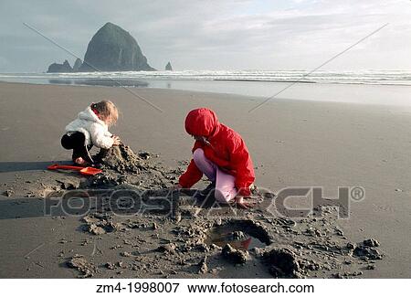 USA, OREGON, CANNON BEACH, CHILDREN PLAYING IN SAND ON BEACH. View Large Photo Image Stock Photo - USA, OREGON, CANNON BEACH, CHILDREN PLAYING IN SAND ON BEACH.. Fotosearch