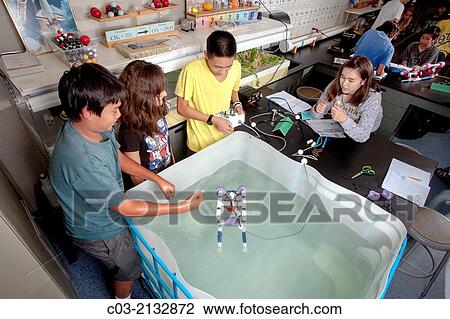 Stock Image - Using a laboratory tank, multiracial middle school students in Mission Viejo, CA, test the remote operated vehicle (ROV) they built in their robotics classroom.. Fotosearch