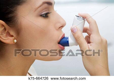 Stock Photograph - Using an inhaler. Fotosearch