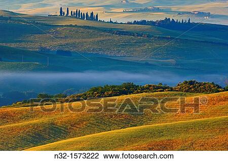 Stock Image - Val d? Orcia at dawn, morning fog, Tuscany landscape, UNESCO world heritage site, San Quirico d? Orcia, Siena province, Tuscany, Italy. Fotosearch