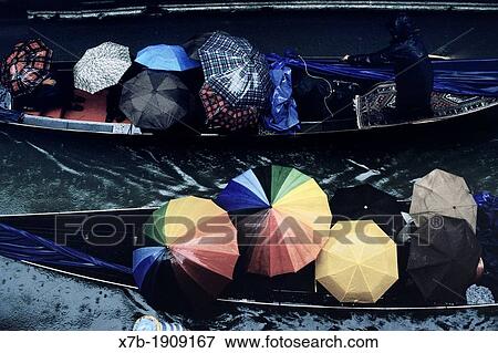 Stock Photo - Venice Italy Gondolas packed with tourists holding umbrellas in the pouring rain. Fotosearch