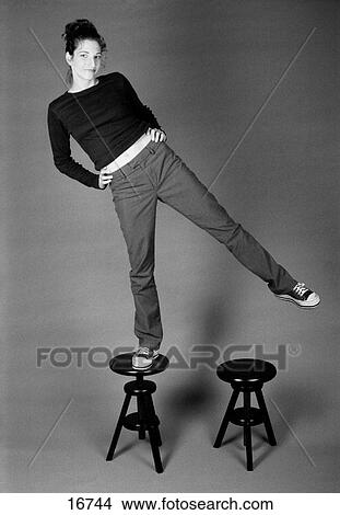 Vertical, b/w studio portrait of girl balancing on stool View Large Photo Image Picture - Vertical, b/w studio portrait of girl balancing on stool. Fotosearch