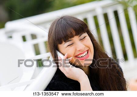 Very happy young woman is using a cellular phone View Large Photo Image Stock Photo - Very happy young woman is using a cellular phone. Fotosearch