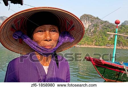 Stock Image - Vietnam, Halong Bay, Old woman in purple in fishing village. Fotosearch
