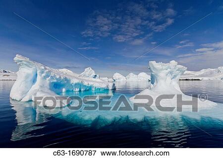 Stock Photo - View of calm seas, icebergs, and reflected mountains surrounding Damoy Point from the National Geographic Explorer in Dorian Bay, Antarctica. Fotosearch