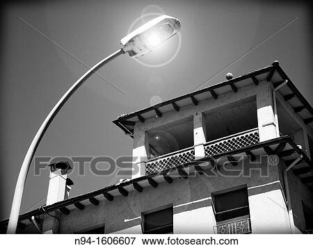 Stock Photo - View of the facade of a house lit by street lamps.. Fotosearch