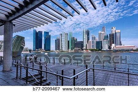 view of the Singapore skyline across Marina Bay from the Marina Sands Waterfront Promenade boardwalk. View Large Photo Image Stock Photo - view of the Singapore skyline across Marina Bay from the Marina Sands Waterfront Promenade boardwalk.. Fotosearch