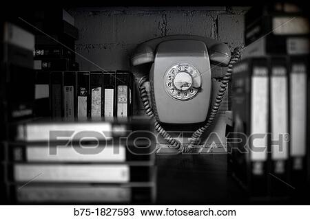 Stock Image - Vintage Telephone group dim with VHS movies.. Fotosearch