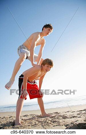 Stock Image - Virginia Beach, Virginia, USA, 2 boys playing on the beach, 13 years old.. Fotosearch