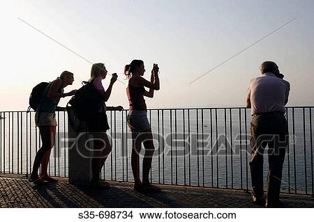 Visitors look at the Sorrento Bay from a lookout from top of the coast cliff. Sorrento. Campania. Italy View Large Photo Image Picture - Visitors look at the Sorrento Bay from a lookout from top of the coast cliff. Sorrento. Campania. Italy. Fotosearch