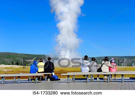 Stock Image - Visitors View Old Faithful Geyser Yellowstone National Park Wyoming, WY. Fotosearch