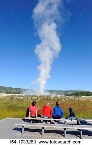 Stock Image - Visitors View Old Faithful Geyser Yellowstone National Park Wyoming, WY. Fotosearch