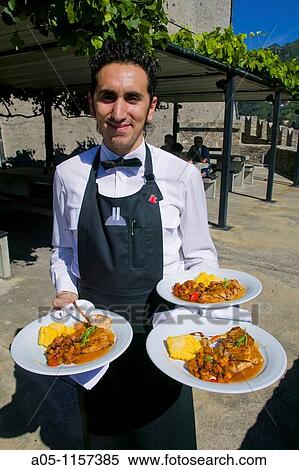 Waiter. Gastronomy. Polenta cornmeal porridge with rabbit and ratatouille stewed vegetable dish. Bellinzona. Ticino. Switzerland. View Large Photo Image Stock Photography - Waiter. Gastronomy. Polenta cornmeal porridge with rabbit and ratatouille stewed vegetable dish. Bellinzona. Ticino. Switzerland.. Fotosearch