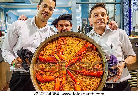 Waiters show a paella. In La Pepica restaurant, 6 Passeig Nept, Malvarrosa beach. Valencia, Spain. View Large Photo Image Picture - Waiters show a paella. In La Pepica restaurant, 6 Passeig Nept, Malvarrosa beach. Valencia, Spain.. Fotosearch