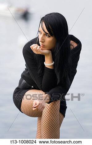 Picture - Waiting young woman in Black, boat in background. Fotosearch