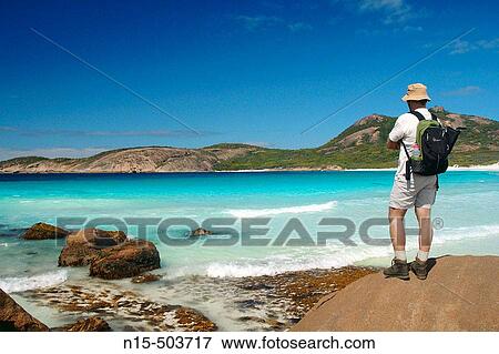 Walker on the Coastal Track pauses to take in stunning colours of Thistle Bay, Cape Le Grand National Park, near Esperance, Western Australia. View Large Photo Image Stock Photo - Walker on the Coastal Track pauses to take in stunning colours of Thistle Bay, Cape Le Grand National Park, near Esperance, Western Australia.. Fotosearch