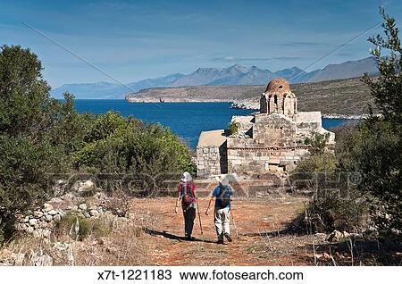 Stock Image - Walkers aproaching the little Byzantine church of Vlacherna near Mezapos in the Deep Mani, Southern Peloponnese, Greece. Fotosearch