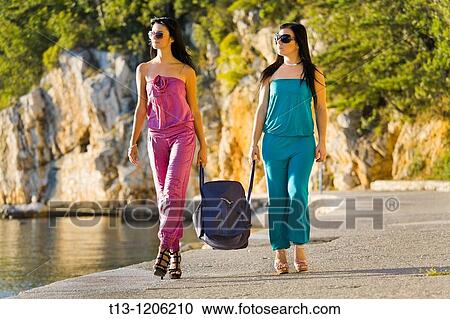 Walking and carrying a big transport bag two young women View Large Photo Image Stock Image - Walking and carrying a big transport bag two young women. Fotosearch