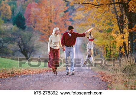 Stock Image - walking country road with their dog. Fotosearch