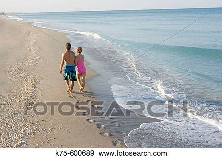 Stock Photo - Walking on deserted beach arm in arm. Fotosearch