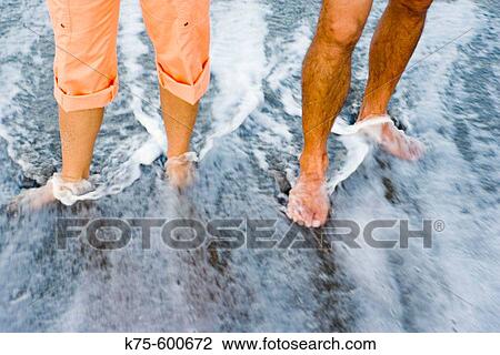 Stock Image - Walking through the surf on beach. Fotosearch