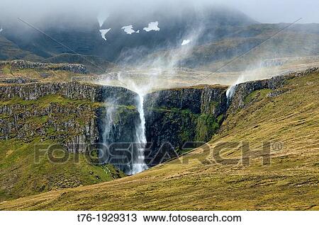 Stock Image - water blown up a waterfall by the wind at Grundisfjordur, Iceland. Fotosearch