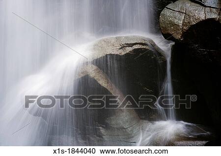 Stock Image - Water fall crashing over boulder. Fotosearch