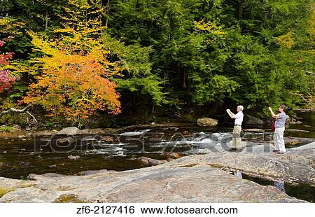 Stock Photograph - Waterville Vermont tourist taking pictures on falls under covered bridge Montgomery Covered Bridge with fall foliage in Northern New England 2.. Fotosearch