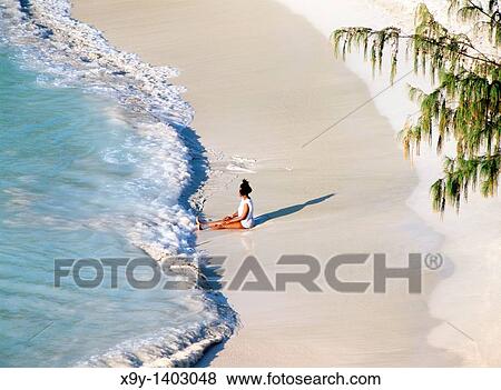 Stock Photo - Waves break on white sand beach Young woman relaxing at Jolly Beach, Coco Beach, west coast of Caribbean island of Antiqua. Fotosearch