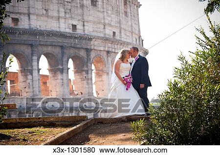 Wedding couple kissing in front of the Roman Coliseum in Rome Italy View Large Photo Image Stock Image - Wedding couple kissing in front of the Roman Coliseum in Rome Italy. Fotosearch
