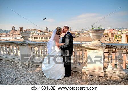 Wedding couple kissing on a balcony in Campidoglio overlooking Rome Italy View Large Photo Image Stock Image - Wedding couple kissing on a balcony in Campidoglio overlooking Rome Italy. Fotosearch