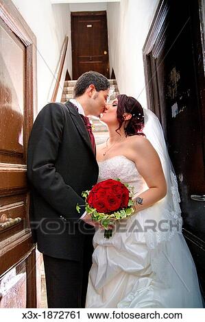 Wedding couple kissing on a doorstep View Large Photo Image Stock Image - Wedding couple kissing on a doorstep. Fotosearch