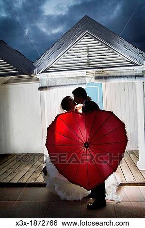 Wedding couple kissing with a red umbrella Ostia Rome Italy View Large Photo Image Stock Photograph - Wedding couple kissing with a red umbrella Ostia Rome Italy. Fotosearch