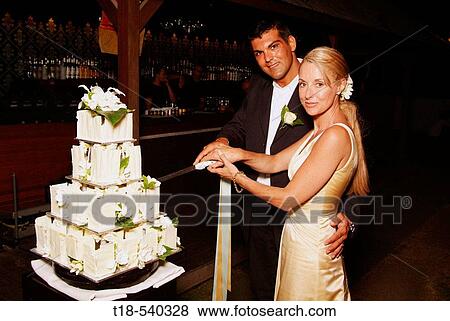 Stock Photo - wedding couple slicing cake. Fotosearch