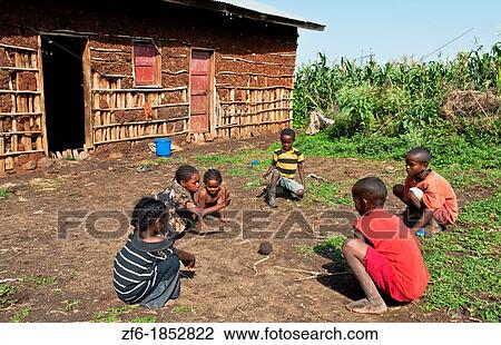 Stock Image - Weliata Sodo Ethiopia Africa Gamo tribe home with children playing game in front of poor farm house 10. Fotosearch