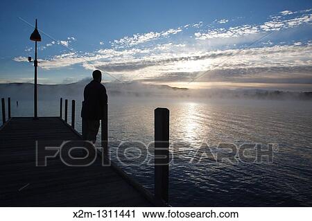 Wellington State Park - The silhouette of a man on dock watching sunrise over Newfound Lake in Bristol, New Hampshire USA View Large Photo Image Stock Image - Wellington State Park - The silhouette of a man on dock watching sunrise over Newfound Lake in Bristol, New Hampshire USA. Fotosearch