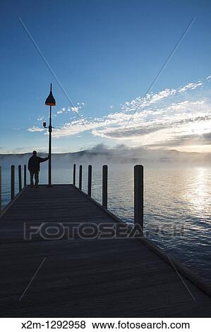 Wellington State Park - The silhouette of a man on dock watching sunrise over Newfound Lake in Bristol, New Hampshire USA View Large Photo Image Stock Photo - Wellington State Park - The silhouette of a man on dock watching sunrise over Newfound Lake in Bristol, New Hampshire USA. Fotosearch