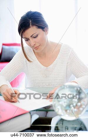 Stock Photo - White dressed 40s woman working over the table. Fotosearch