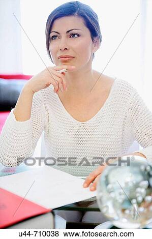 Stock Photo - White dressed 40s woman working over the table. Fotosearch