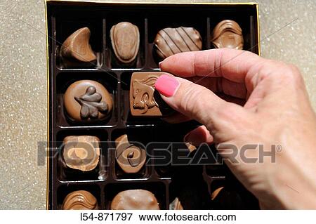 White female hand selects candy from box of premium variety chocolates View Large Photo Image Stock Photo - White female hand selects candy from box of premium variety chocolates. Fotosearch