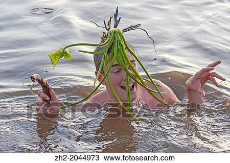 Stock Image - White male 30-35 years old swimming and having fun on vacation with a flower on his head in Boden, Norrbotten, Sweden.. Fotosearch