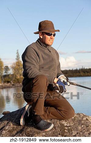 Stock Photo - White man fishing in a river in swedish lapland in autumn season. Fotosearch