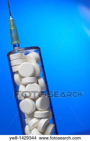 Picture - White tablets in syringe shaped container. Fotosearch
