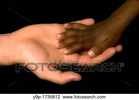 Stock Image - White woman's hand receive the black child's hand. Fotosearch