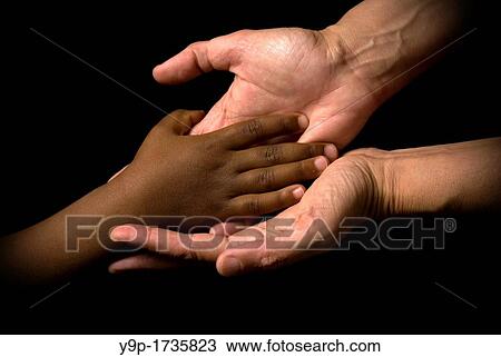 Stock Image - White woman's hands receive the black child's hand. Fotosearch