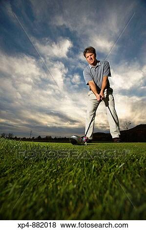 Wide angle image of a golfer lining up a shot with a dramatic sky in background. View Large Photo Image Stock Photo - Wide angle image of a golfer lining up a shot with a dramatic sky in background.. Fotosearch