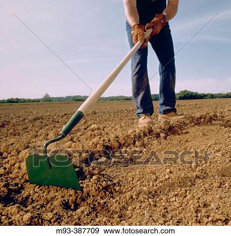 Wideangle and low view of green hoe blade as farmer works soil in a large tilled field. Farmers face not visible. View Large Photo Image Stock Photo - Wideangle and low view of green hoe blade as farmer works soil in a large tilled field. Farmers face not visible.. Fotosearch