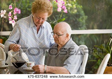 Wife pours coffee for her husband in sunroom. View Large Photo Image Stock Photo - Wife pours coffee for her husband in sunroom.. Fotosearch