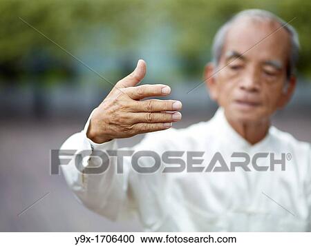 Stock Image - William Ng, a Tai Chi master practicing Tai Chi on the deck of The Peninsula Hotel, overlooking Hong Kong Victoria Harbour skyline. Fotosearch